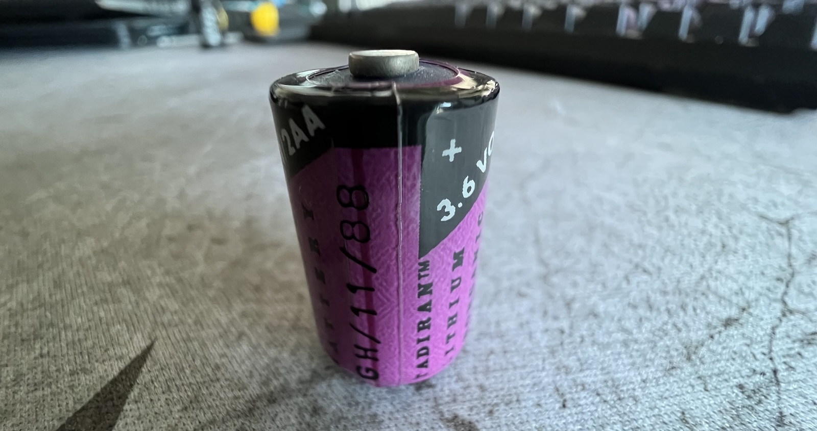 A 1/2AA sized battery sitting on my desk. The battery label indicates that it is a Tadiran lithium battery, 3.6 volts, and a manufacture date of November 1988.